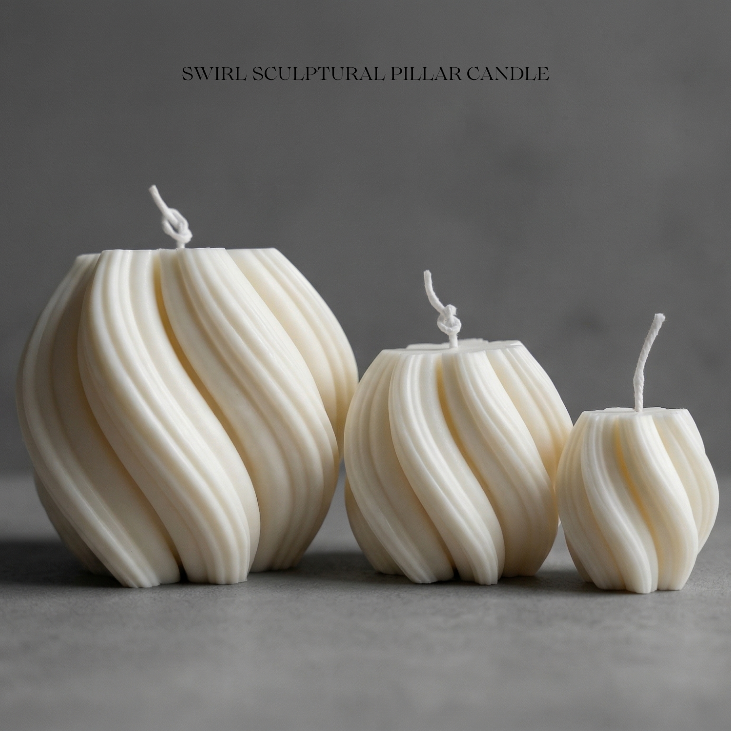 Three swirl sculptural pillar candles on a gray background