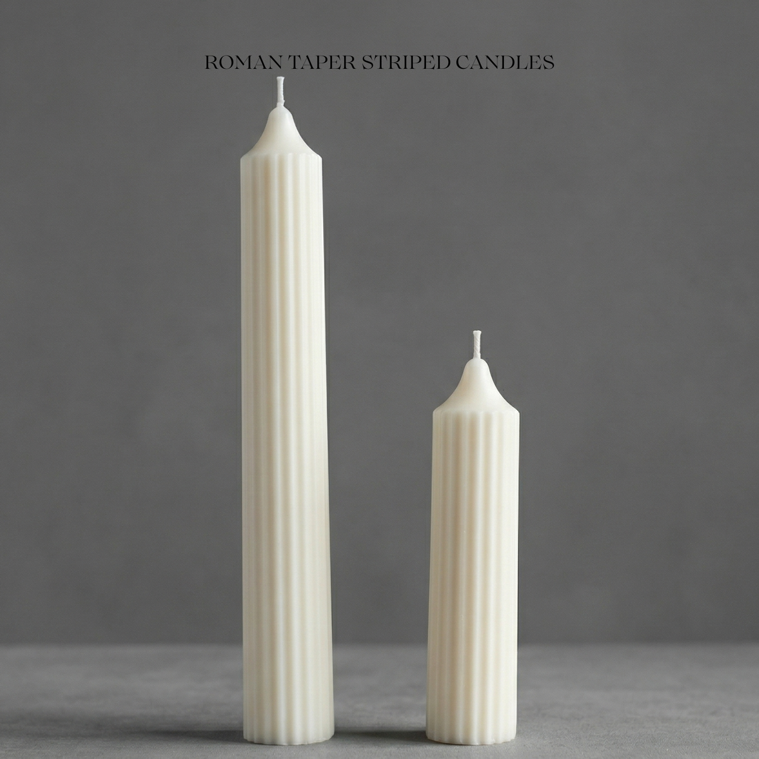 Two white striped candles on a gray surface with a dark gray background