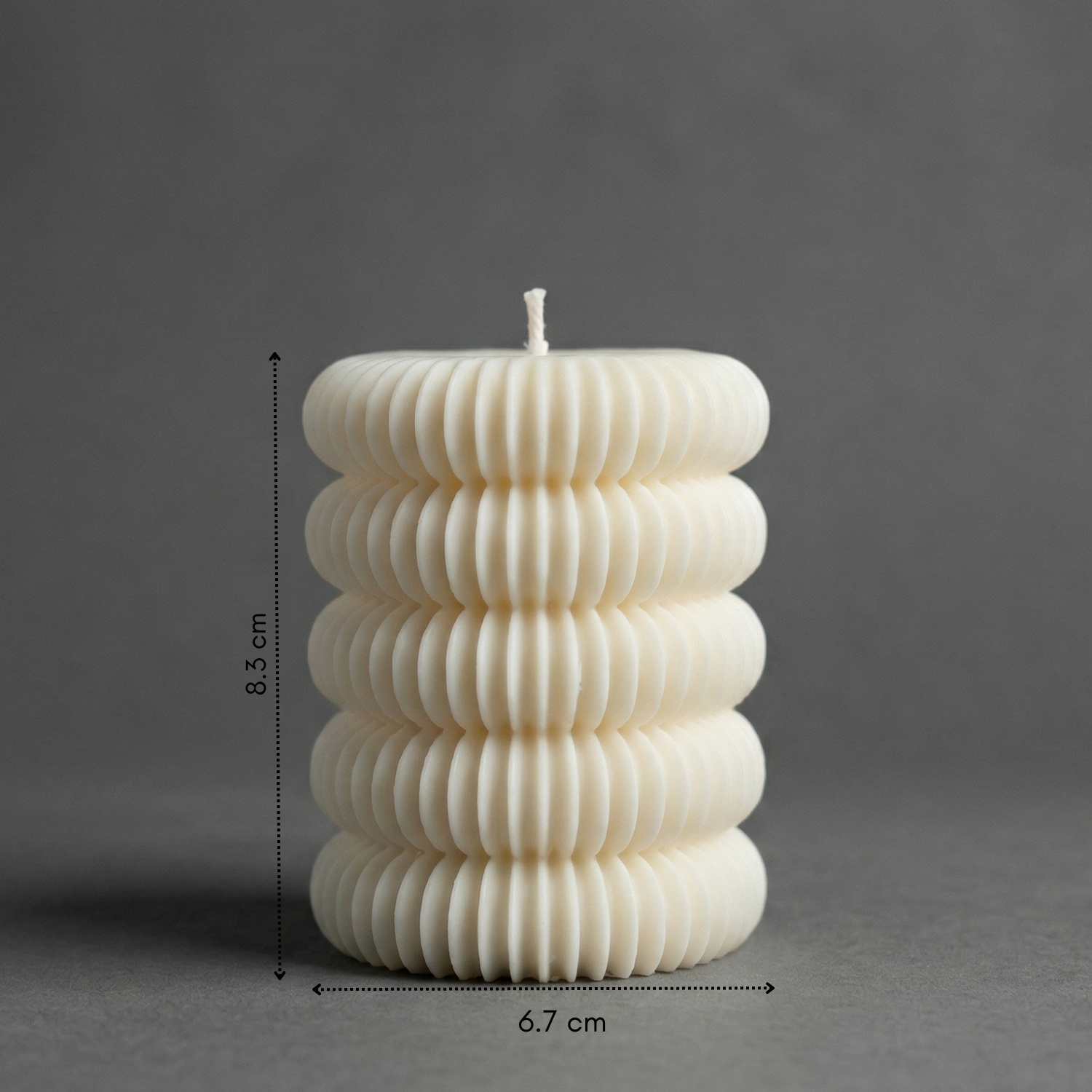 White ribbed candle with measurements on a gray background