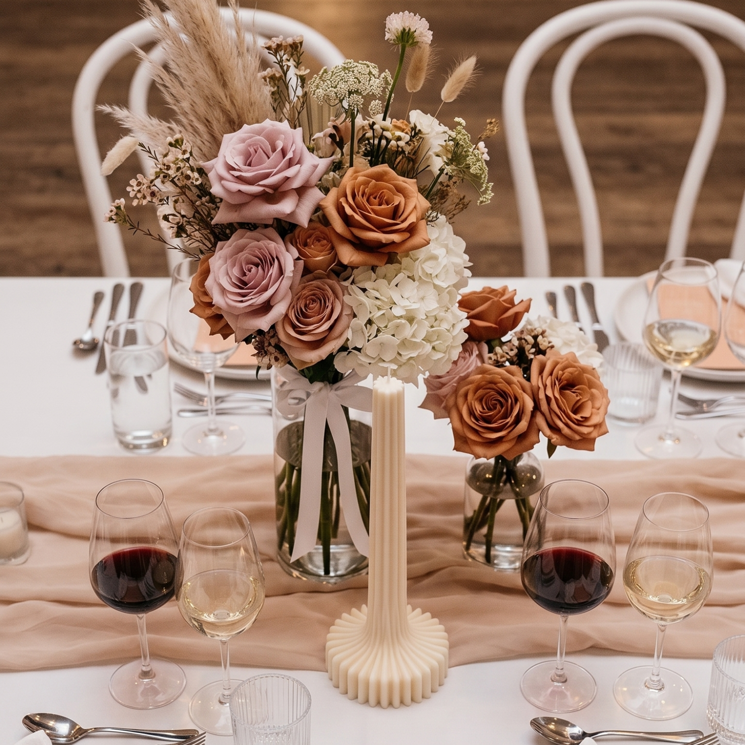 Decorative floral arrangement on a table with wine glasses and cutlery.