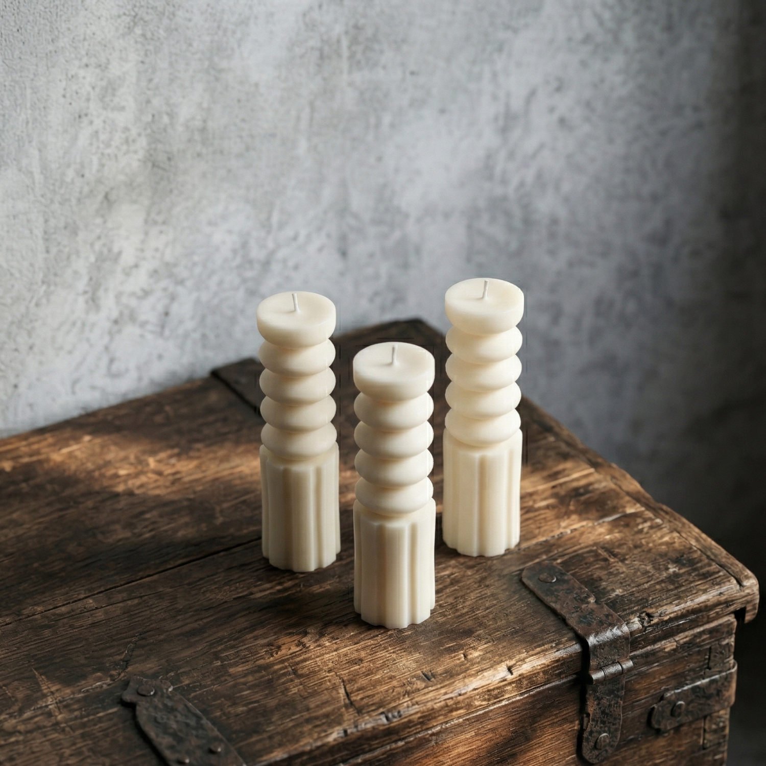 Three textured candles on a wooden surface with a gray background