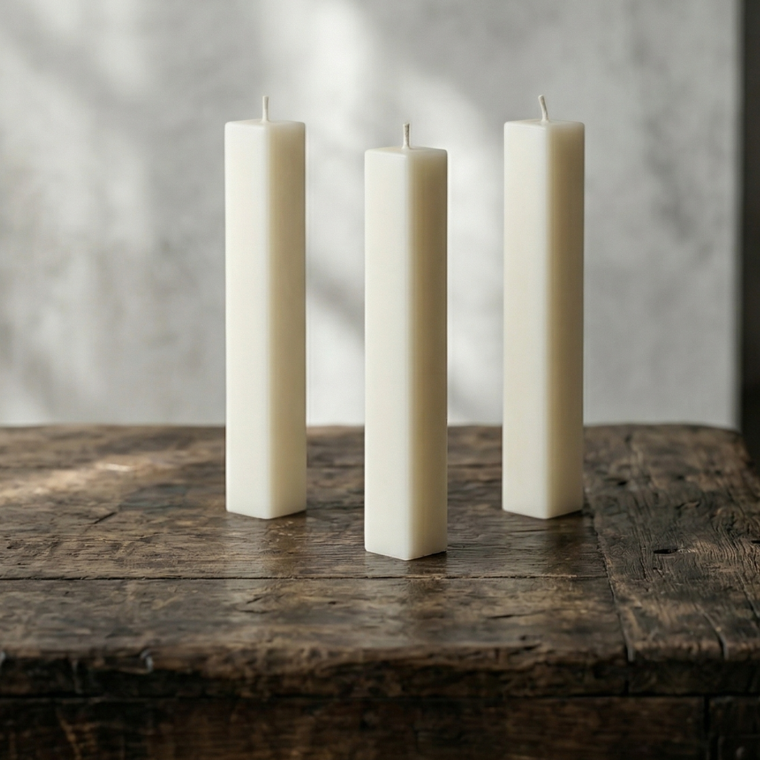 Three white candles on a wooden surface with a gray background