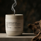 Candle labeled 'Indochine Golden Sunset' with smoke rising, placed on a wooden surface.