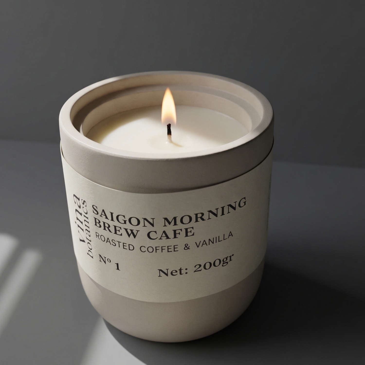 Candle in a white container labeled 'Saigon Morning Brew Cafe' on a dark background