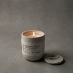 Candle in a beige container with a label on a gray background