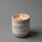 Candle in a white container with a label on a gray background