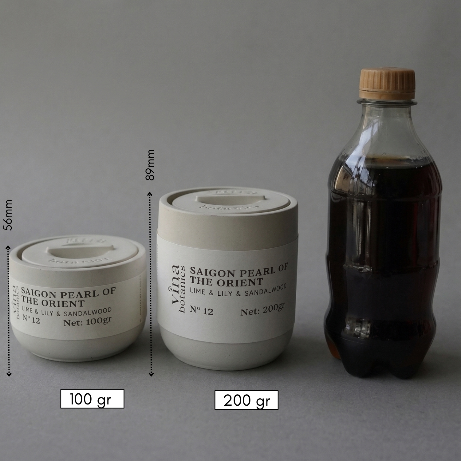Two containers labeled 'Saigon Pearl of the Orient' with measurements and a bottle on a gray background