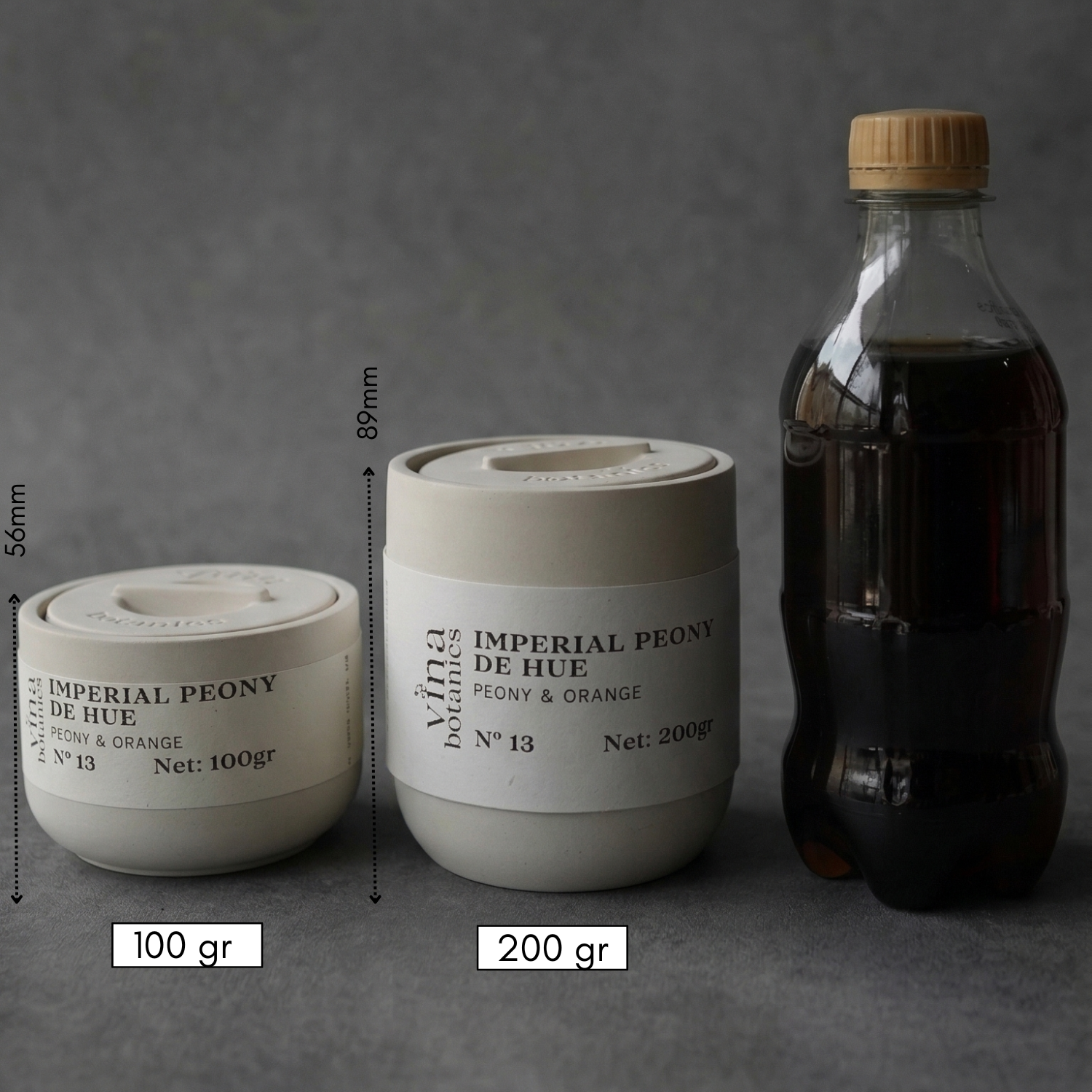 Two cylindrical containers with labels and a bottle on a gray background, showing measurements and weights.