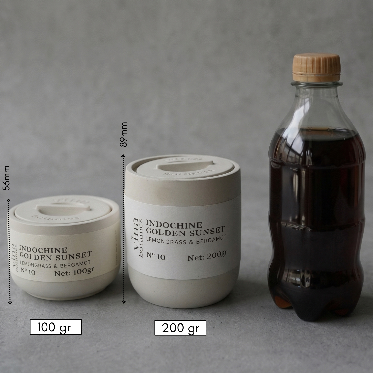 Two containers labeled 'Indochine Golden Sunset' with measurements and a bottle of dark liquid on a gray background.