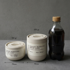 Two containers labeled 'Saigon Morning Brew Cafe' and a bottle on a gray surface with a dark background.