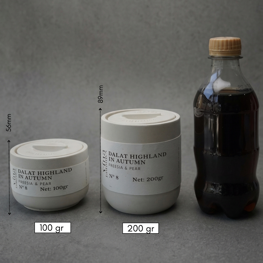 Two containers labeled 'Dalat Highland in Autumn' with measurements and a bottle on a gray background